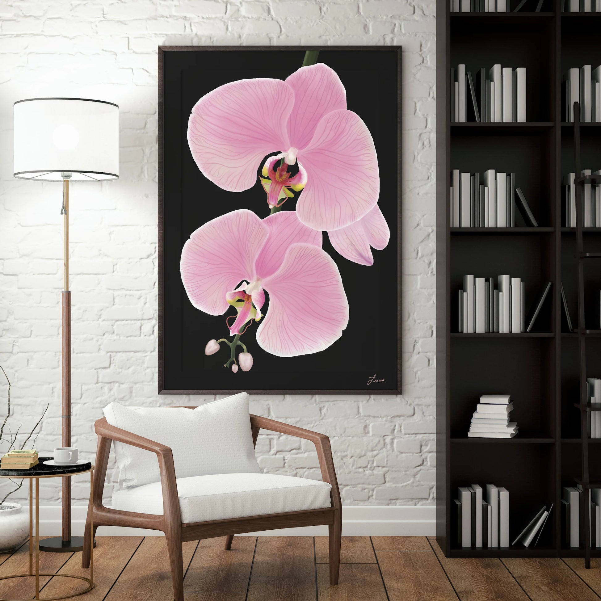A modern living room with a white brick wall features a large premium canvas painting of two pink orchid flowers. There’s a white armchair with wooden arms, a black floor lamp, a round side table, and a tall black bookshelf filled with books.