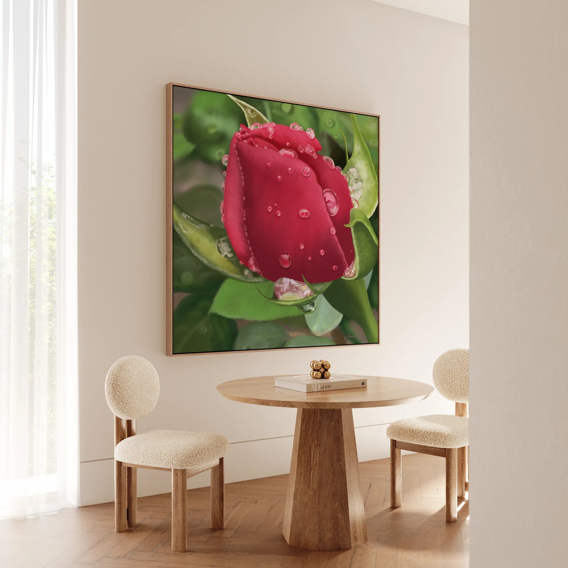 Minimalist dining nook with two curved cream chairs and a round wooden table. On the wall, a red rose canvas in a floating wood frame, with water droplets and green leaves, adds allure as light filters in through sheer curtains on the left.