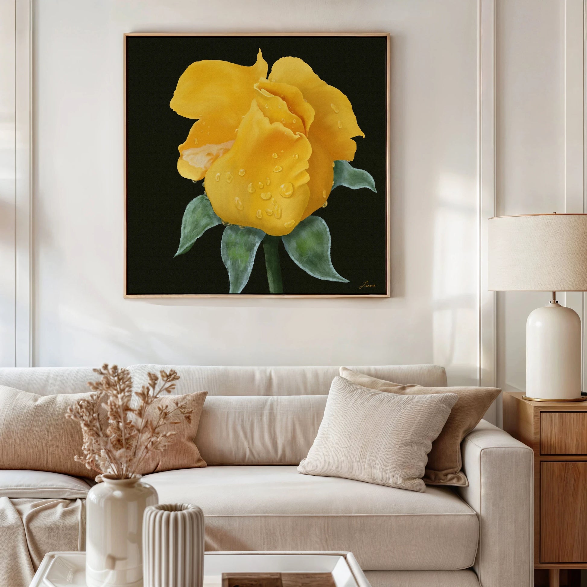 A living room with a beige couch, cream pillows, a dried flower arrangement on a coffee table, and a wooden side table with a lamp features premium canvas print yellow rose artwork with water droplets as the striking focal point on the wall.