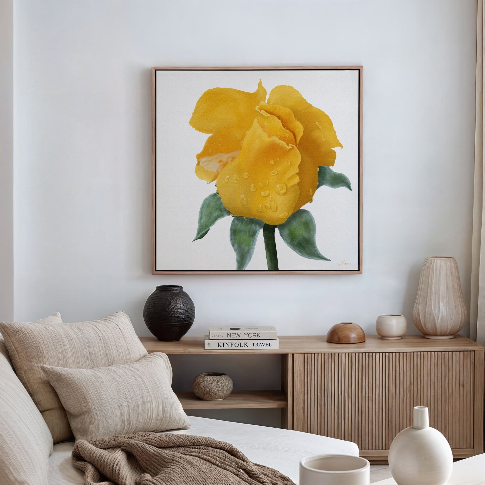 A cozy living room with a beige sofa, cushions, and a wooden sideboard decorated with vases and books. Above it hangs a vibrant yellow rose canvas art print in floating wood frame options, its petals adorned with glistening water droplets.