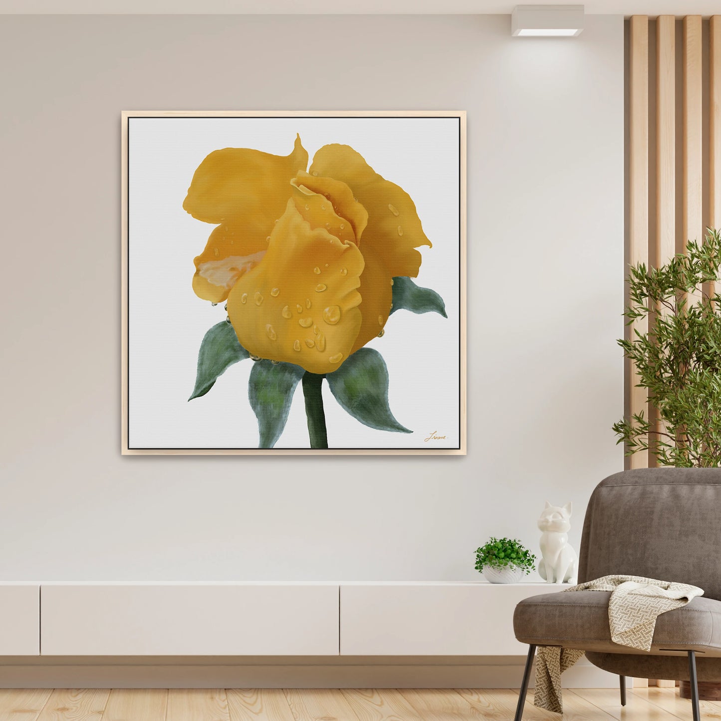 A modern living room featuring a vibrant yellow rose canvas art print with green leaves and water droplets, mounted above a low white shelf. Contemporary interiors are accented by a potted plant, cat figurine, and folded blanket.