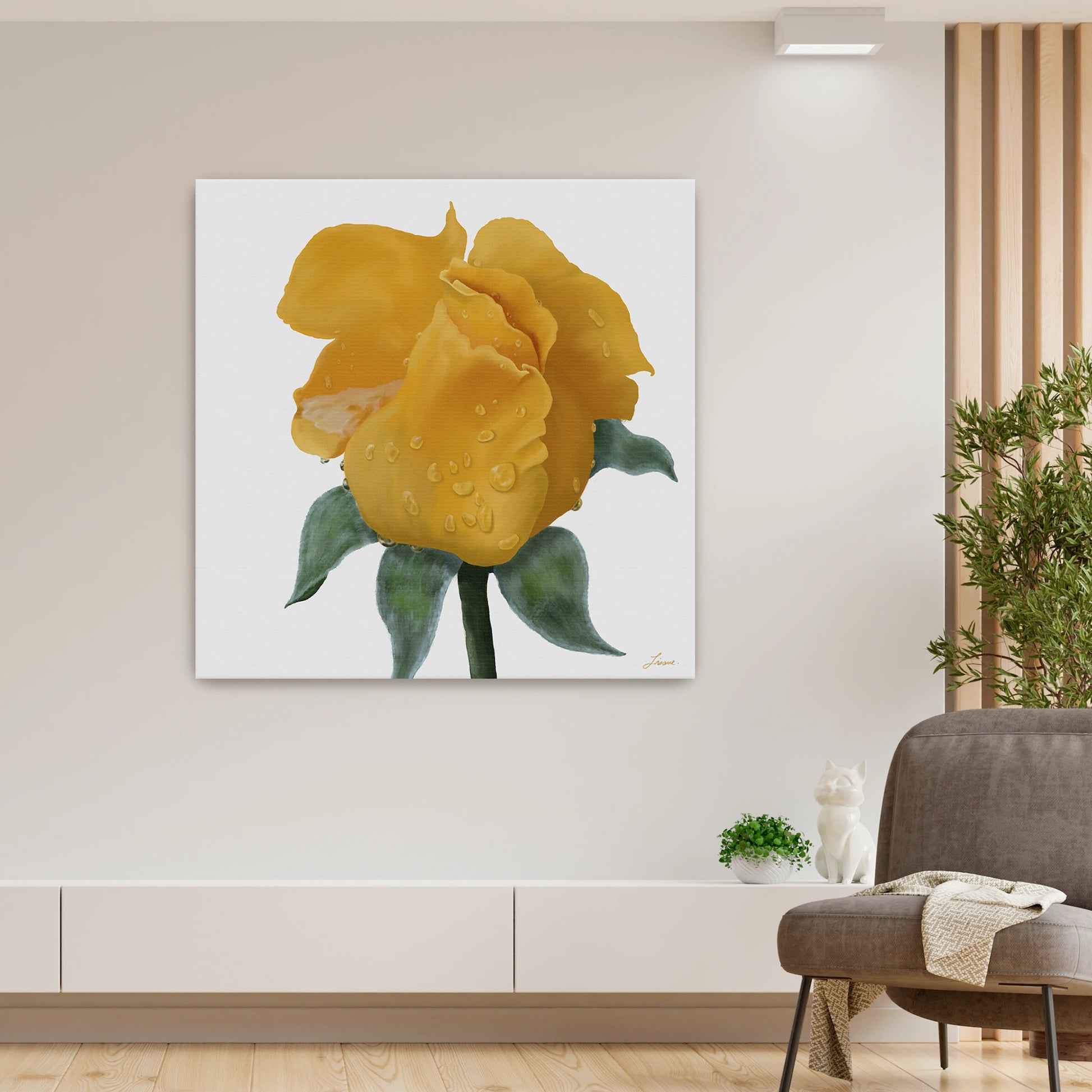 A modern living room with beige walls features a vibrant yellow rose canvas art print, hung above a low white console. A small plant, a white cat figurine, and a gray chair with a blanket add charm while natural light brightens this contemporary interior.