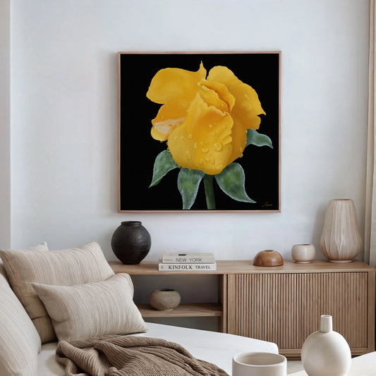 A modern living room with a neutral palette features a wooden console topped with books, a vase, and decor. Above, a canvas art print of a yellow rose with green leaves and water droplets stands out against a black background.