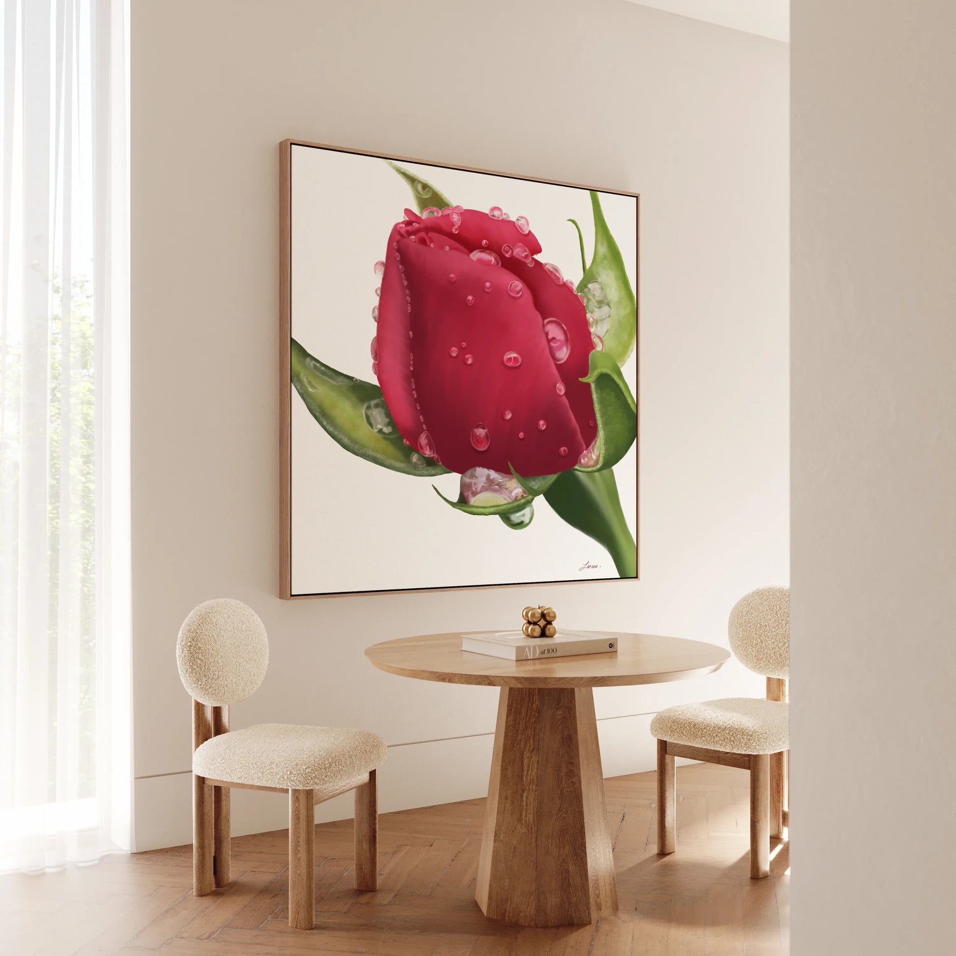 A minimal dining nook features a round wooden table with two textured, cream-upholstered chairs. On the wall hangs Refreshing Love, a realistic red rosebud on gallery-wrapped canvas, letting soft light filter through sheer curtains.