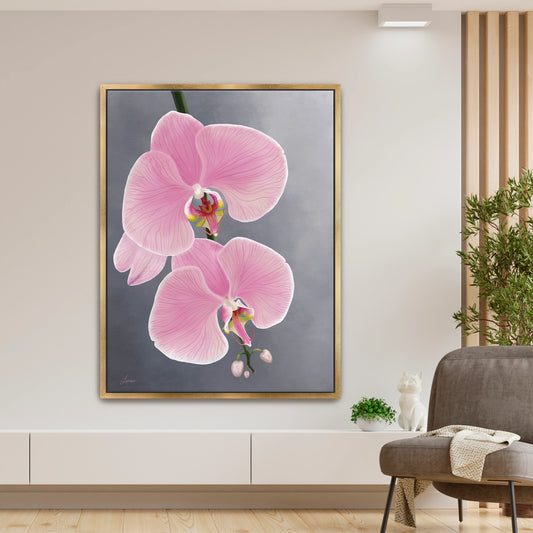 Modern living room featuring a delicate pink orchid canvas art by Lisane Art, with graceful blooms gently reaching toward the right against a soft grey background- elegantly framed in a luxurious gold floating frame. 
